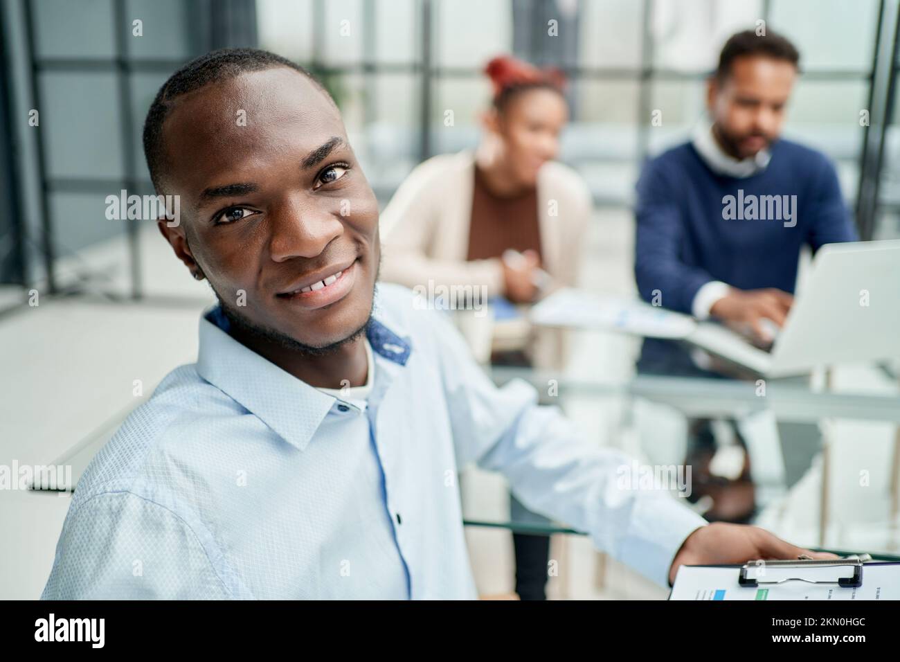 Ein Geschäftsmann mit einer Finanzkarte, der neben einem Büroschreibtisch sitzt. Stockfoto