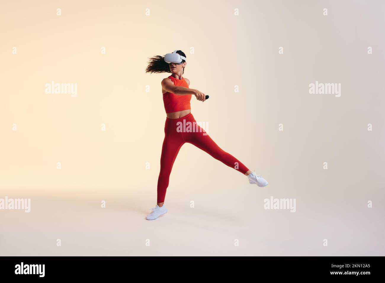 Sportlerin trainiert mit immersiver Technologie. Aktive junge Frau, die ein Virtual-Reality-Fitnessspiel erforscht. Sportliche junge Frau, die eine Tugend trägt Stockfoto