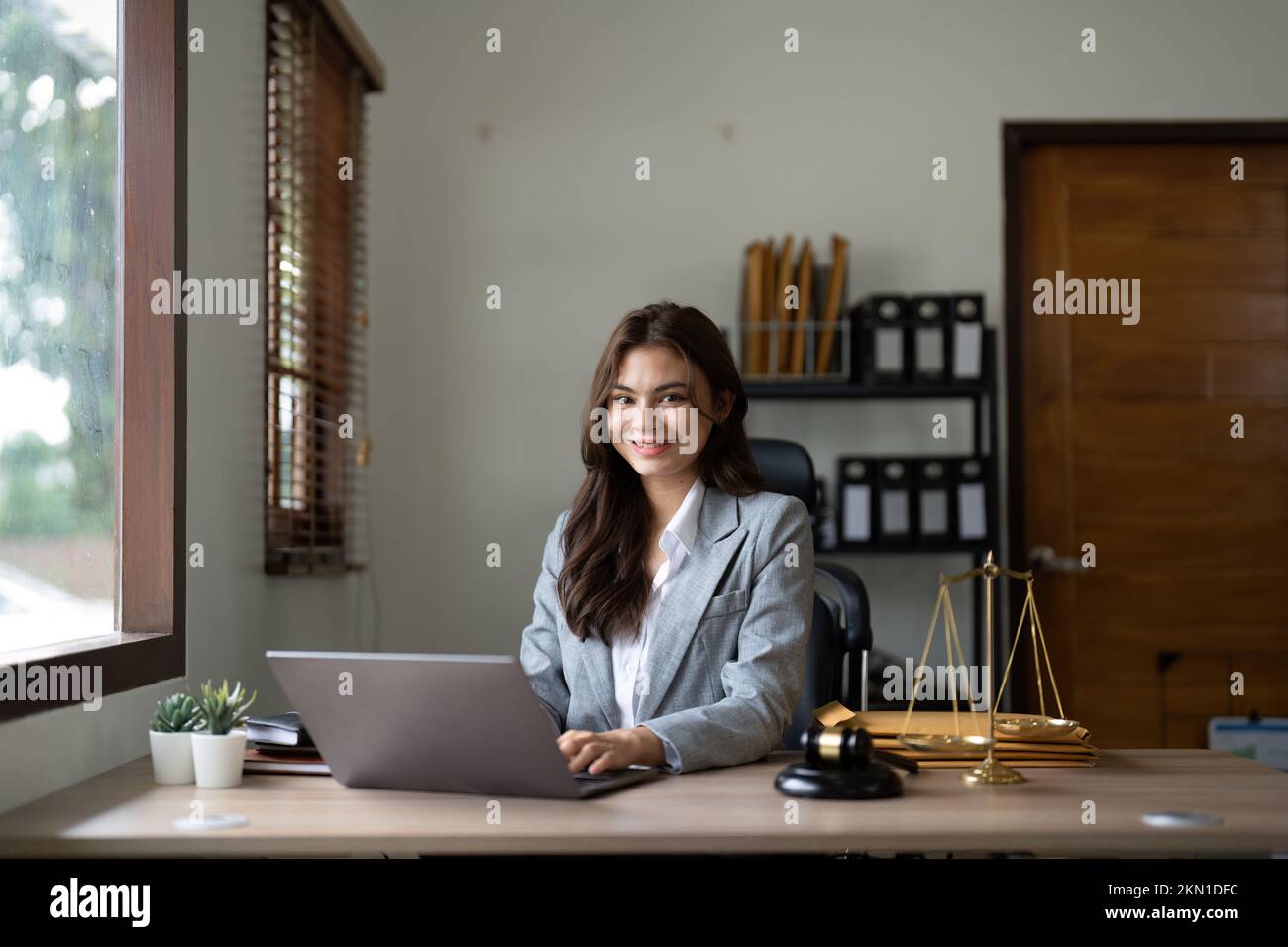 Recht und Gesetz Konzept. Männlicher Richter in einem Gerichtssaal auf einem Holztisch und Anwalt oder Portrait asiatischer Anwalt, der mit lsptop im Amt arbeitet. Recht Stockfoto