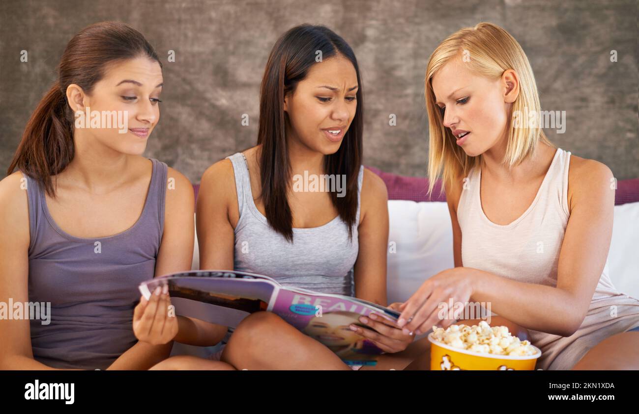 Zeit für Promi-Klatsch. Eine Gruppe von Freunden, die sich durch Zeitschriften stöbern, während sie abhängen. Stockfoto