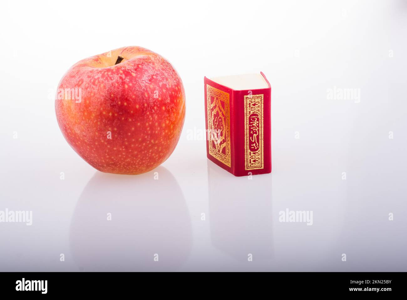 Roter Apfel und islamisches Heiliges Buch Koran in Minigröße Stockfoto