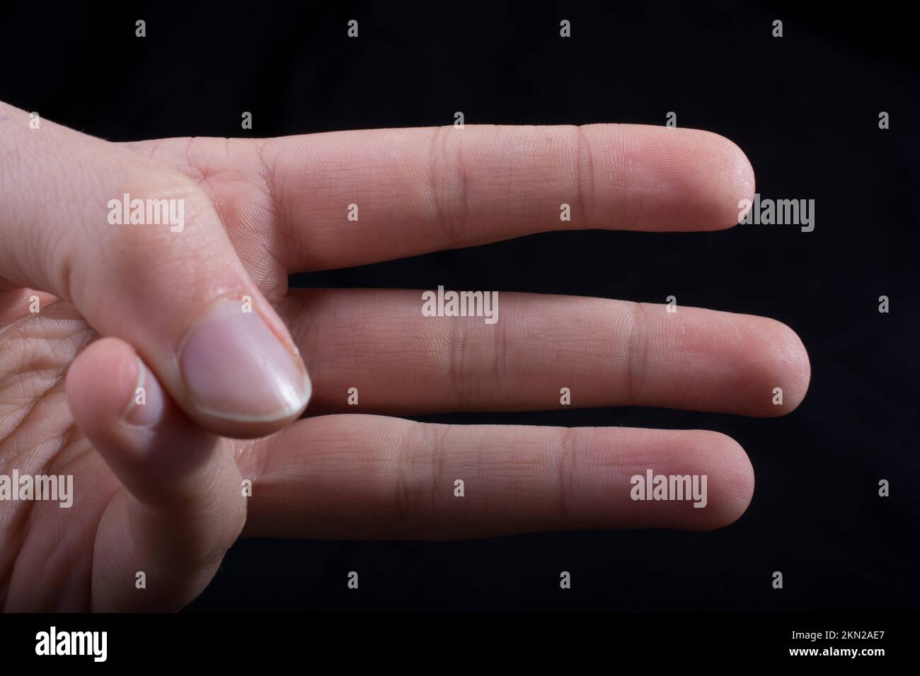 Drei Finger einer Hand des Kindes teilweise in schwarzen Hintergrund gesehen Stockfoto