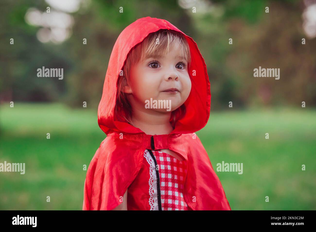 Charmantes Baby in einem roten Motorhaubenkostüm Stockfoto