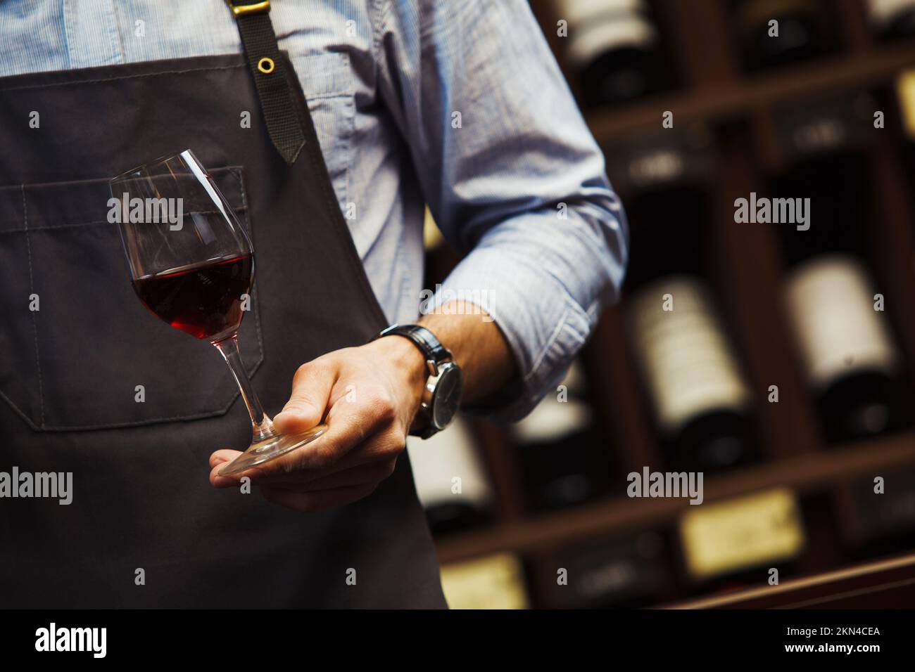 Männlicher Sommelier hält Bokal mit Rotwein in der Hand Stockfoto