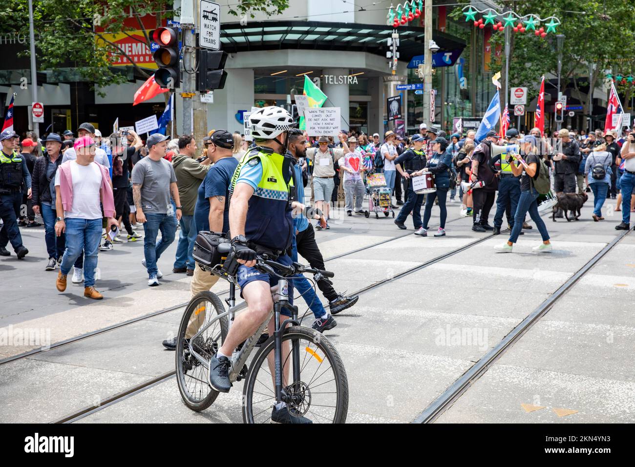 Ein Polizist in Melbourne beobachtet Straßenprotestierende gegen Covid 19-Maßnahmen auf einem Polizeirad und in Shorts, Melbourne, Vic, Australien Stockfoto