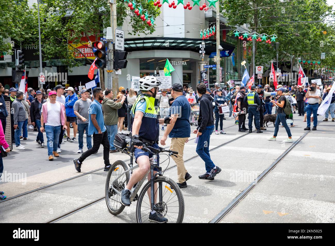 Ein Polizist in Melbourne beobachtet Straßenprotestierende gegen Covid 19-Maßnahmen auf einem Polizeirad und in Shorts, Melbourne, Vic, Australien Stockfoto