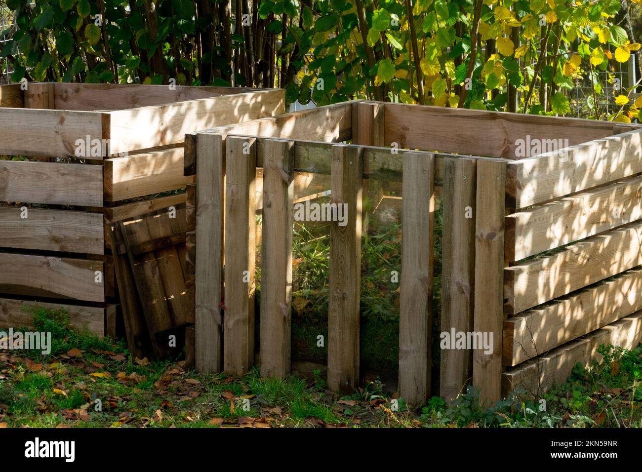 In einem Herbstgarten stellen zwei Holzkomposter im Freien biologisch humushaltige Kompostkästen her Stockfoto