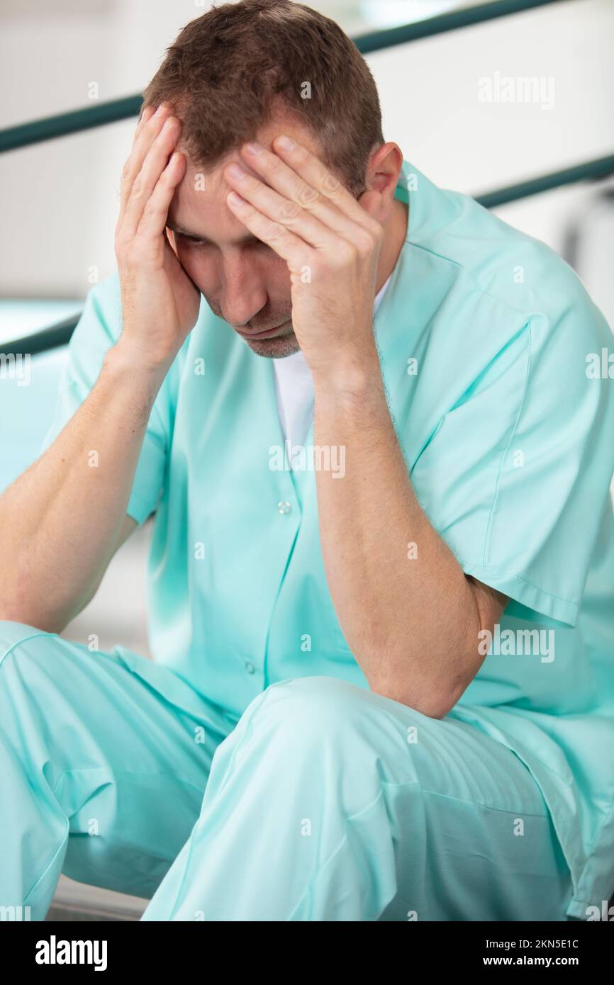 Männliche Krankenschwester gestresst im Krankenhaus Stockfoto
