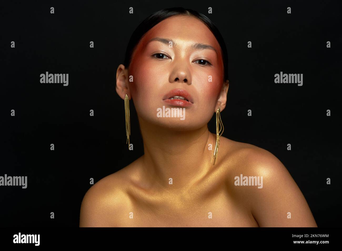 Ein asiatisches Mädchen mit schwarzem Hintergrund im Studio. Gold. Porträt in Schönheitssalons. Stockfoto