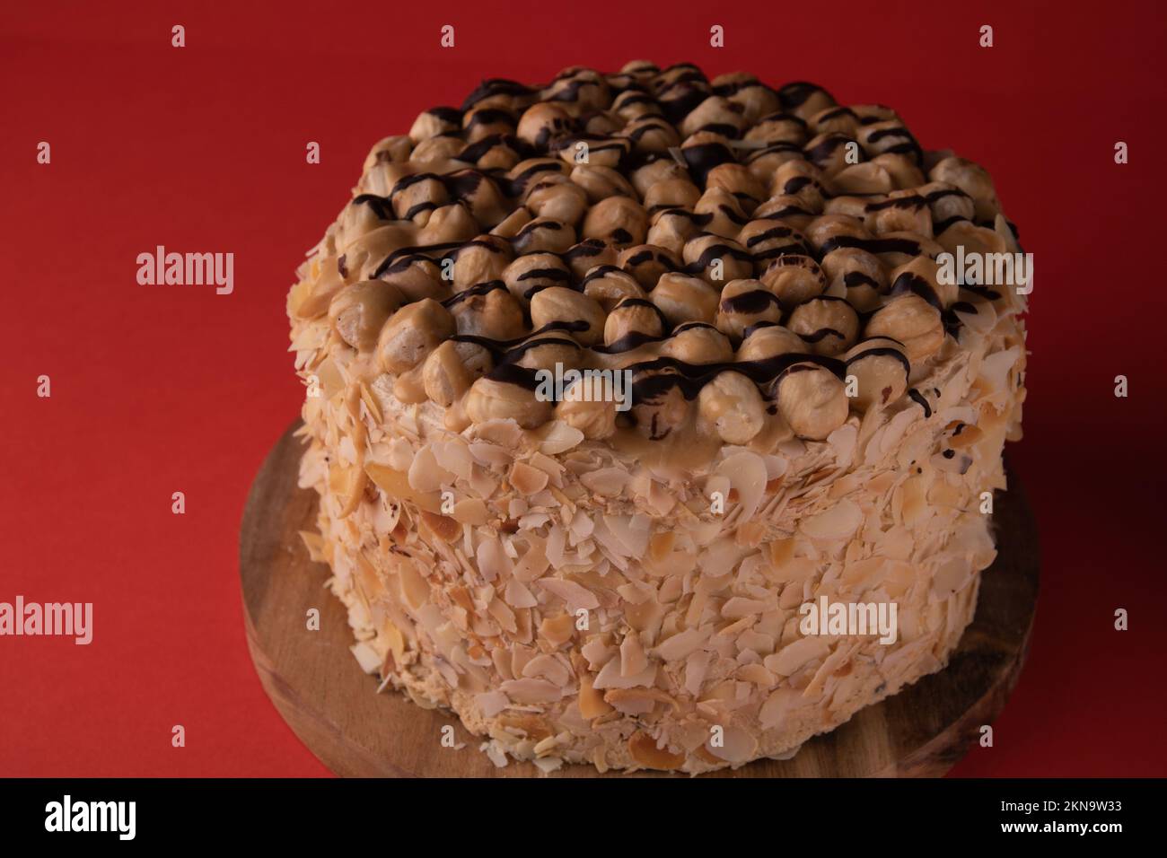 Hoher Walnusskuchen auf einem Holzbrett mit rotem Hintergrund und Seitenansicht Stockfoto