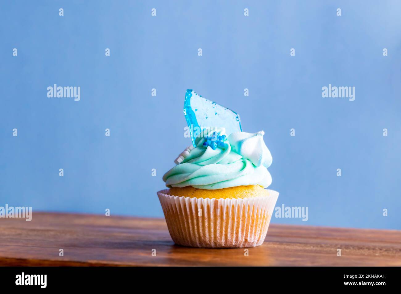 Hausgemachter blauer Cupcake auf einem Holzschreibtisch. Winter- und weihnachtsthema, Schneeflocken auf blauem Eis, frisch und selbstgebacken süß. Stockfoto