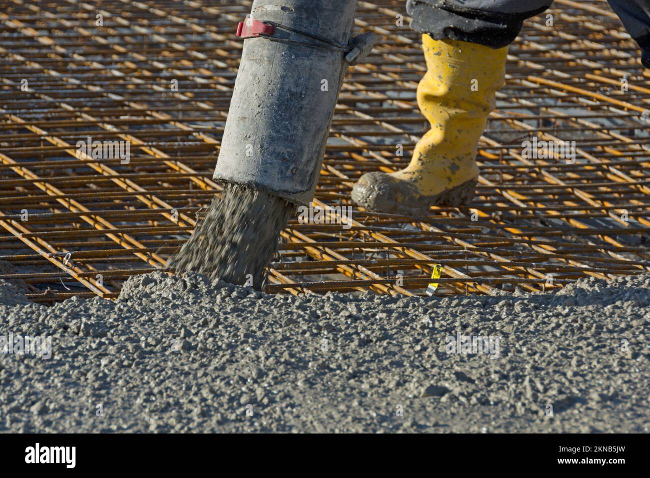 Bauarbeiter gießt Beton mit einer Betonpumpe auf Armierungsstahl Stockfoto