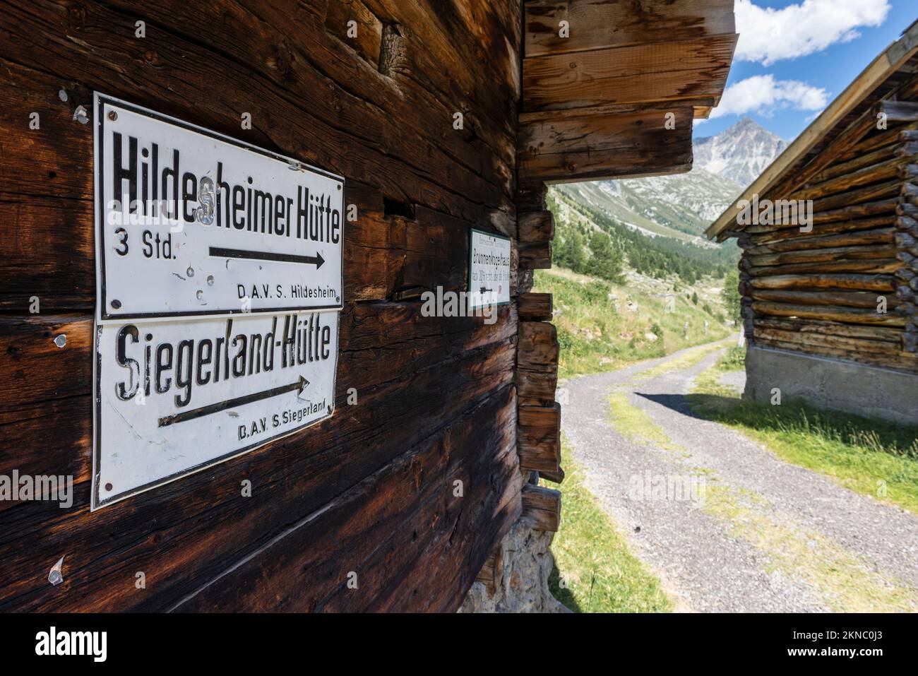 Weiße Wegweiser für den Weg zu den Berghütten in den Ötztalalpen an der hölzernen Mauer einer Bergscheune im Windachtal, Sölden, Österreich Stockfoto