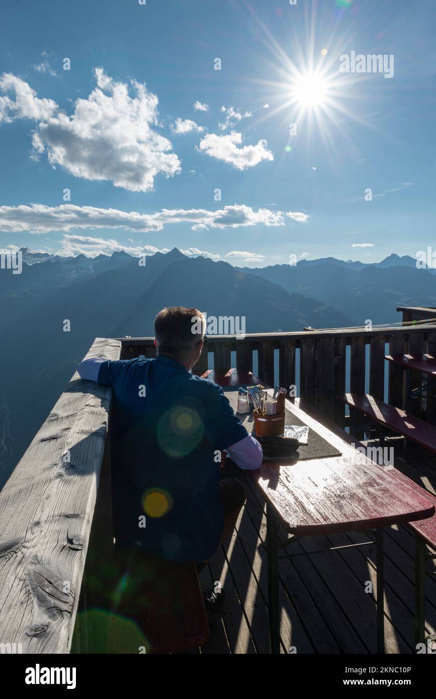 Ein Wanderer sitzt auf der Terrasse der Berghütte Brunnenkogelhaus und blickt auf das Panorama der Ötztalalpen und des Gurgl-Tals in Tirol, Österreich Stockfoto