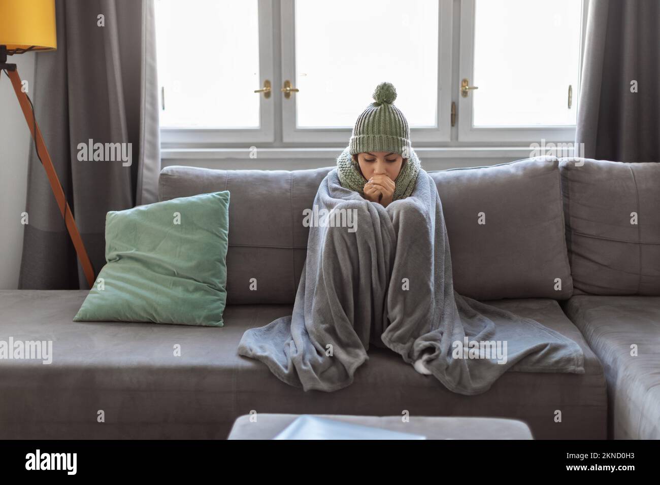 Eine arabische Frau, die zu Hause erkältet war und auf der Couch mit einer Decke saß Stockfoto