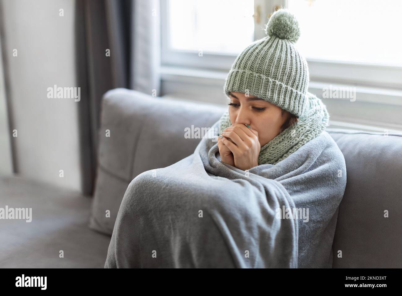 Junge Frau Fühlt Sich Zu Hause Kalt, Sitzt Auf Der Couch, Bedeckt Mit Einer Decke Stockfoto