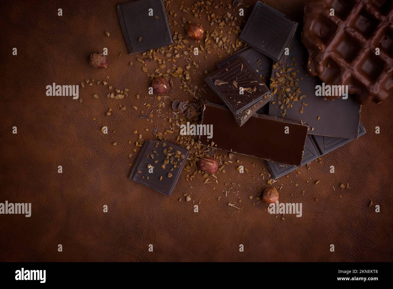 Zusammensetzung von Riegeln und Stücken verschiedener Milch und dunkler Schokolade, geriebener kakaobrauner Hintergrund Draufsicht Stockfoto