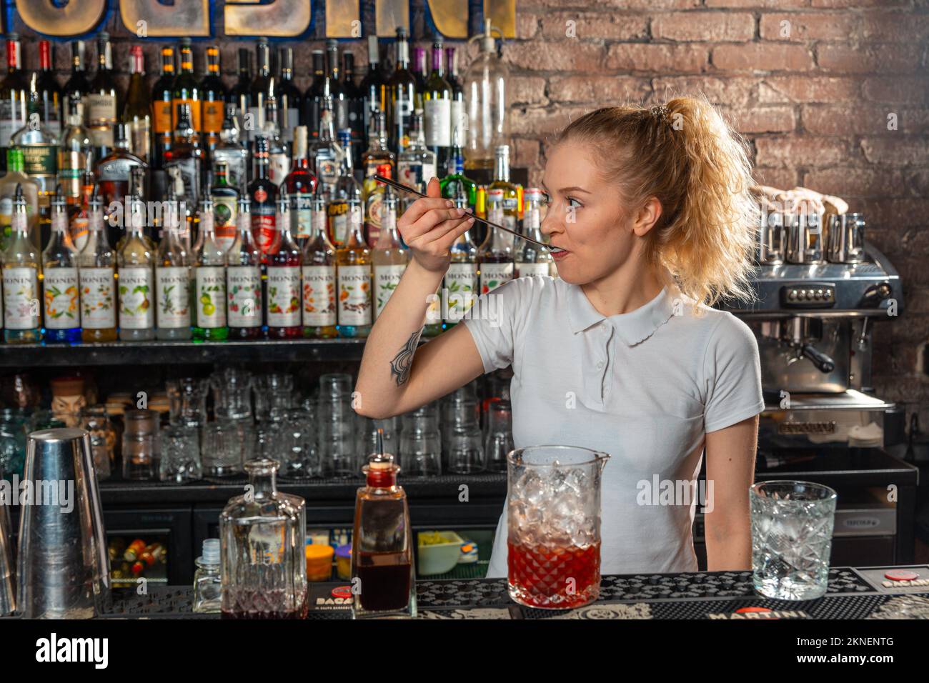 Eine Barkeeperin probiert den zubereiteten Cocktail an der Bar des Nachtclubs. Stockfoto