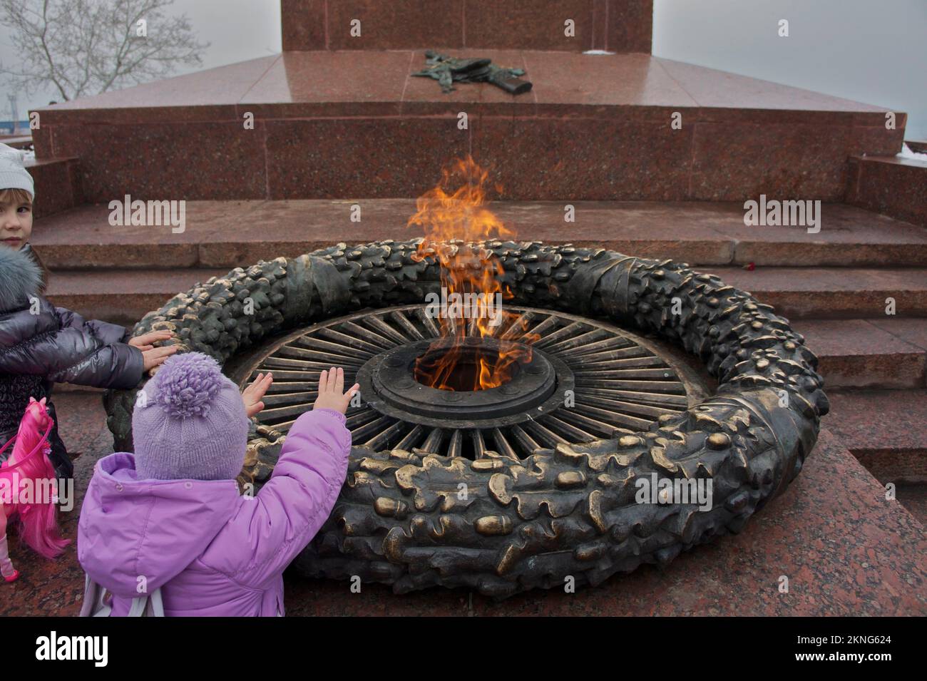 Die Kinder wärmen ihre Hände bei der ewigen Flamme, die diejenigen ehrt, die im großen Krieg starben Stockfoto