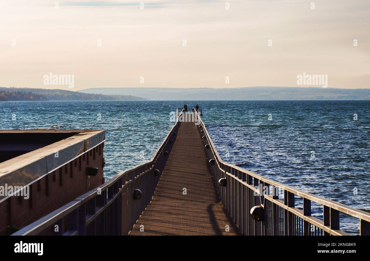 Skaneateles Pier am Skaneateles Lake in der Finger Lakes Region im Bundesstaat New York an einem kalten Herbstmorgen mit zwei unbekannten Männern beim Angeln Stockfoto