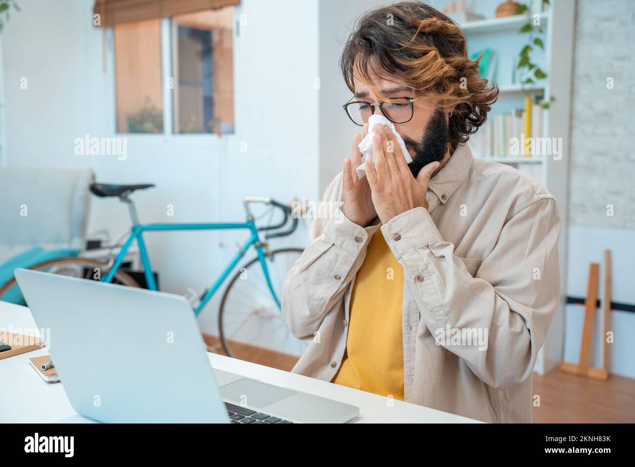 Krank bei der Arbeit junger Mann bekam Grippeallergie Niesen bläst Wischen der Nase im Gewebe Stockfoto