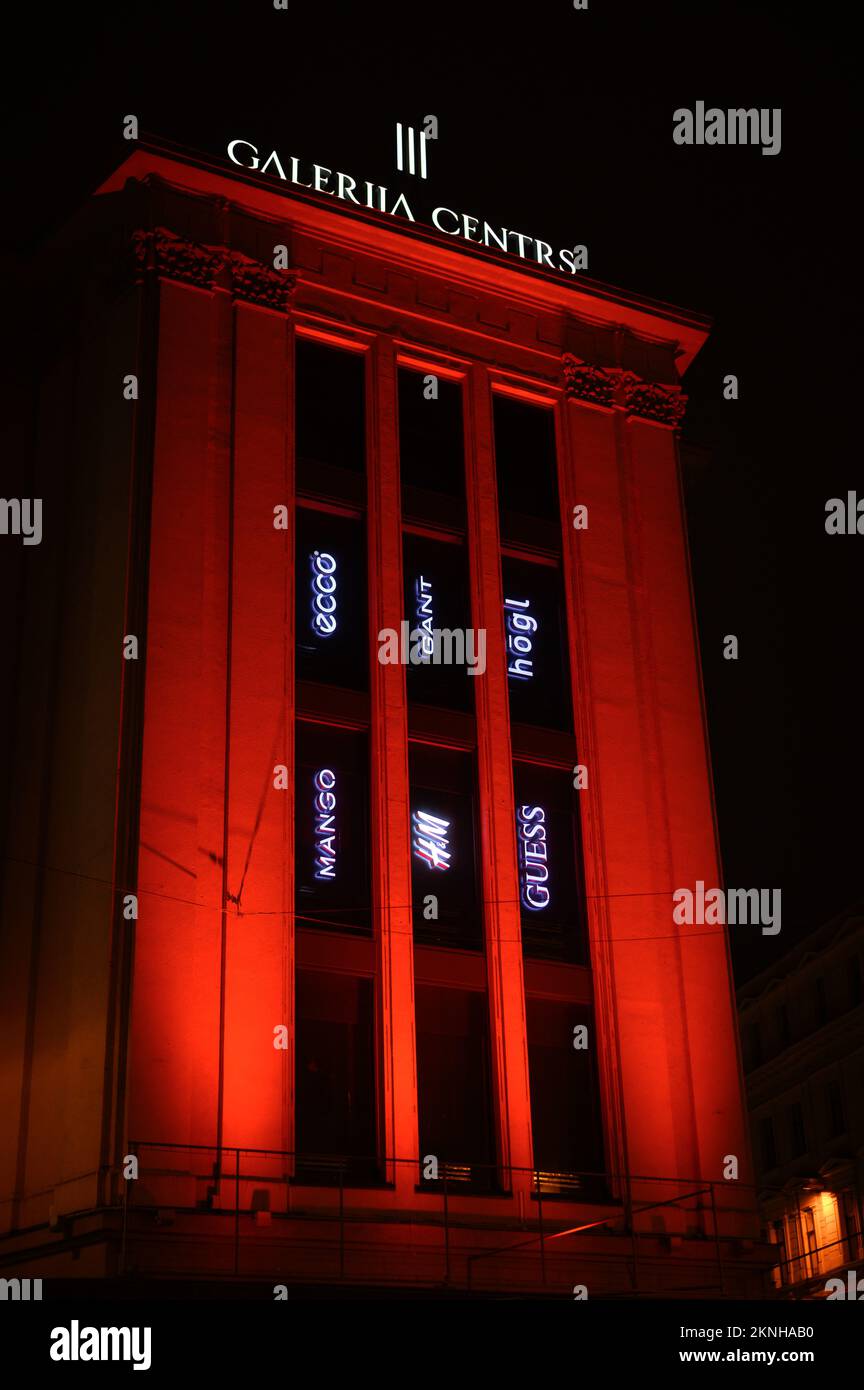 Riga, Lettland, 18. November 2022: Die Eingangstür des Handelszentrums wird nachts rot beleuchtet Stockfoto