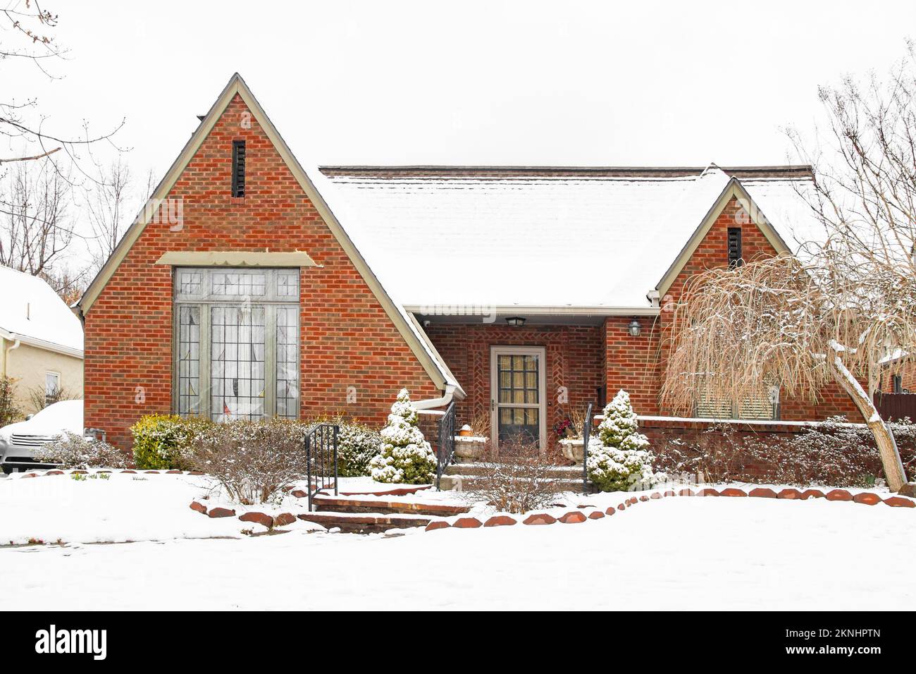 Gepflegtes und ordentliches Backsteinhaus in frischem, kontrastreichen Schnee mit Auto daneben - schön angelegt Stockfoto