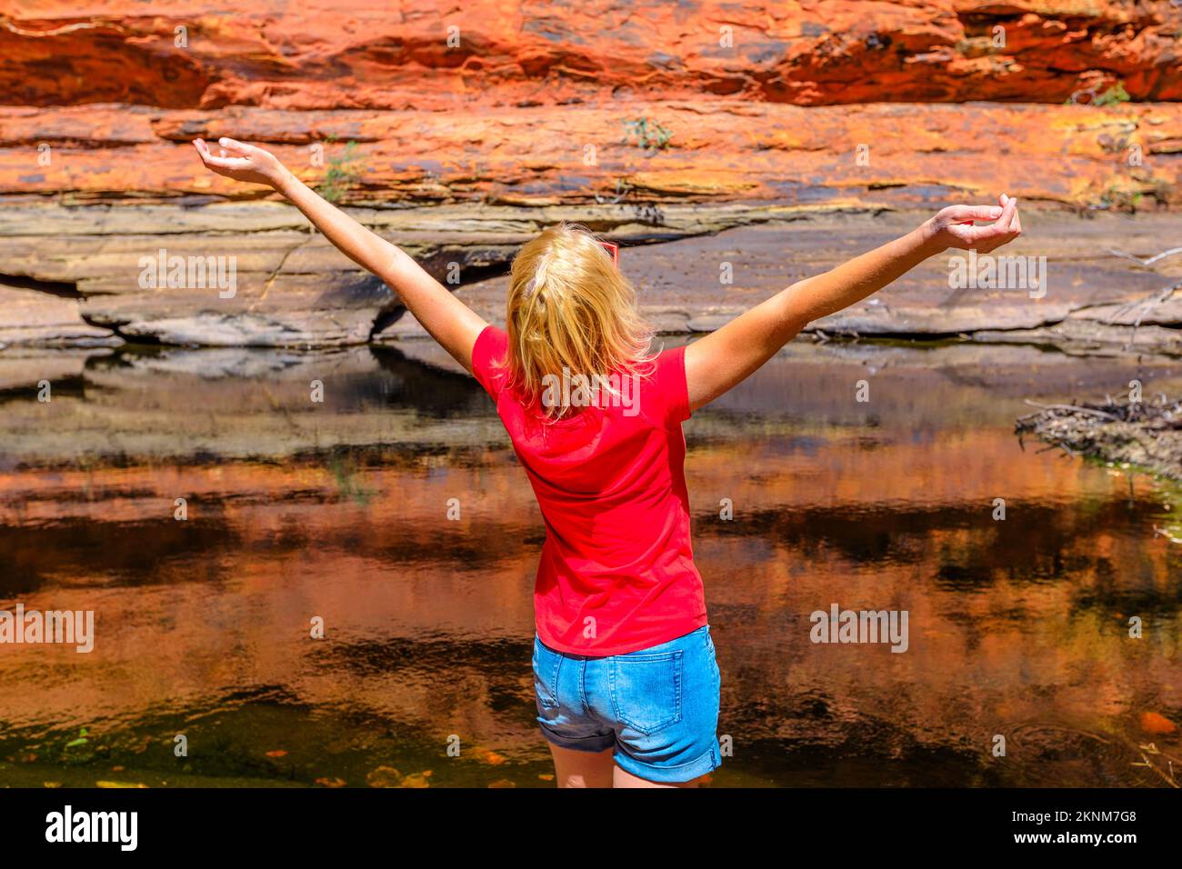 Ein Touristenmädchen genießt nach einer Wanderung im Australia Outback Red Center, Northern Territory, den natürlichen Pool. Wasserloch im Garten Eden reflektierender Sandsto Stockfoto