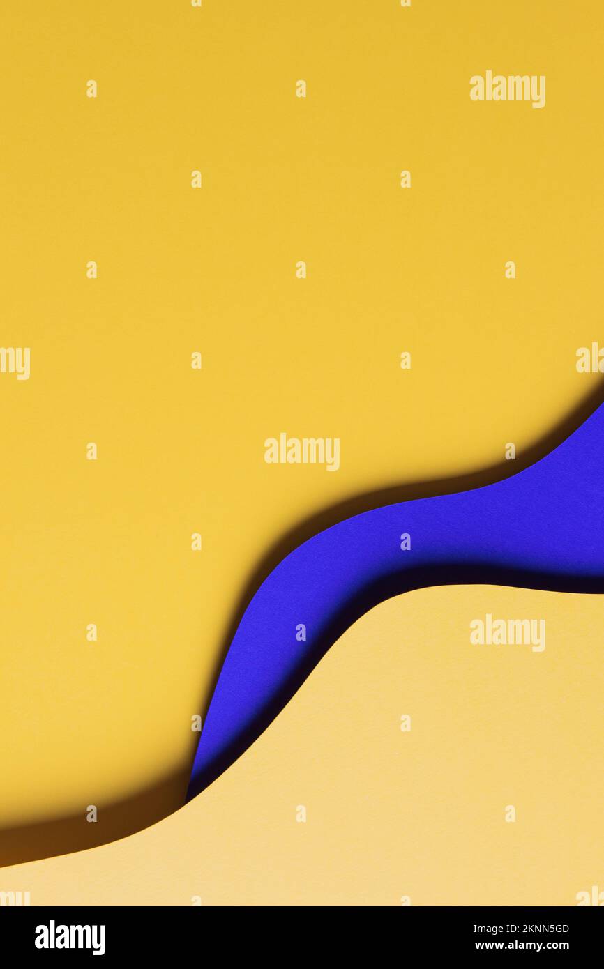 Abstrakter farbiger Papierhintergrund. Minimale Zusammensetzung des Papierschnitts mit Lagen von geometrischen Formen und Linien in Gelb und Blau Stockfoto