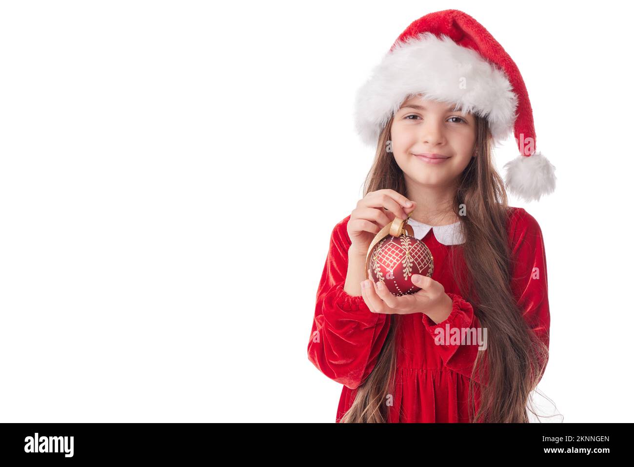Lächelnde Frau mit Weihnachtsbaum leuchtenden Ball, Mädchen posiert in rotem Kleid des Weihnachtsmanns auf weißem Hintergrund Stockfoto