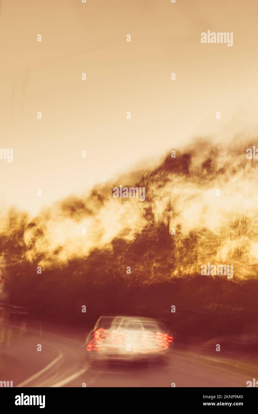 Unkonventionelles Zeitraffer-Foto auf einem altmodischen Auto der 1970er Jahre, das in einer verschwommenen Dämmerungsbeleuchtung davonrast. Verfolgungsjagd auf dem Land Stockfoto