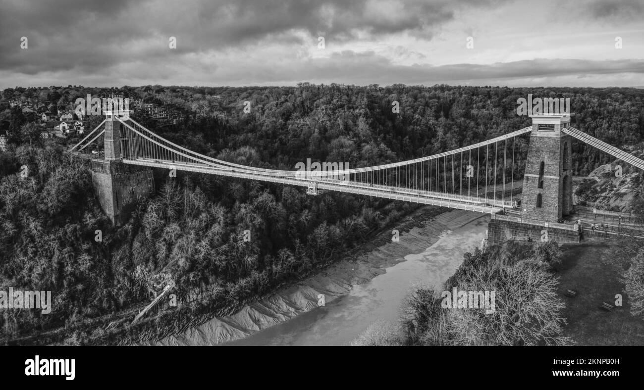 Eine Grauskala einer Clifton Hängebrücke über dem Fluss, umgeben von dichten Bäumen, Bristol, England Stockfoto