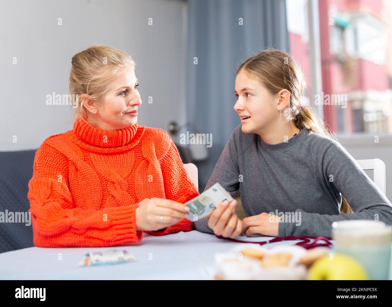 Schülerin nimmt Geld von ihrer Mutter Stockfoto