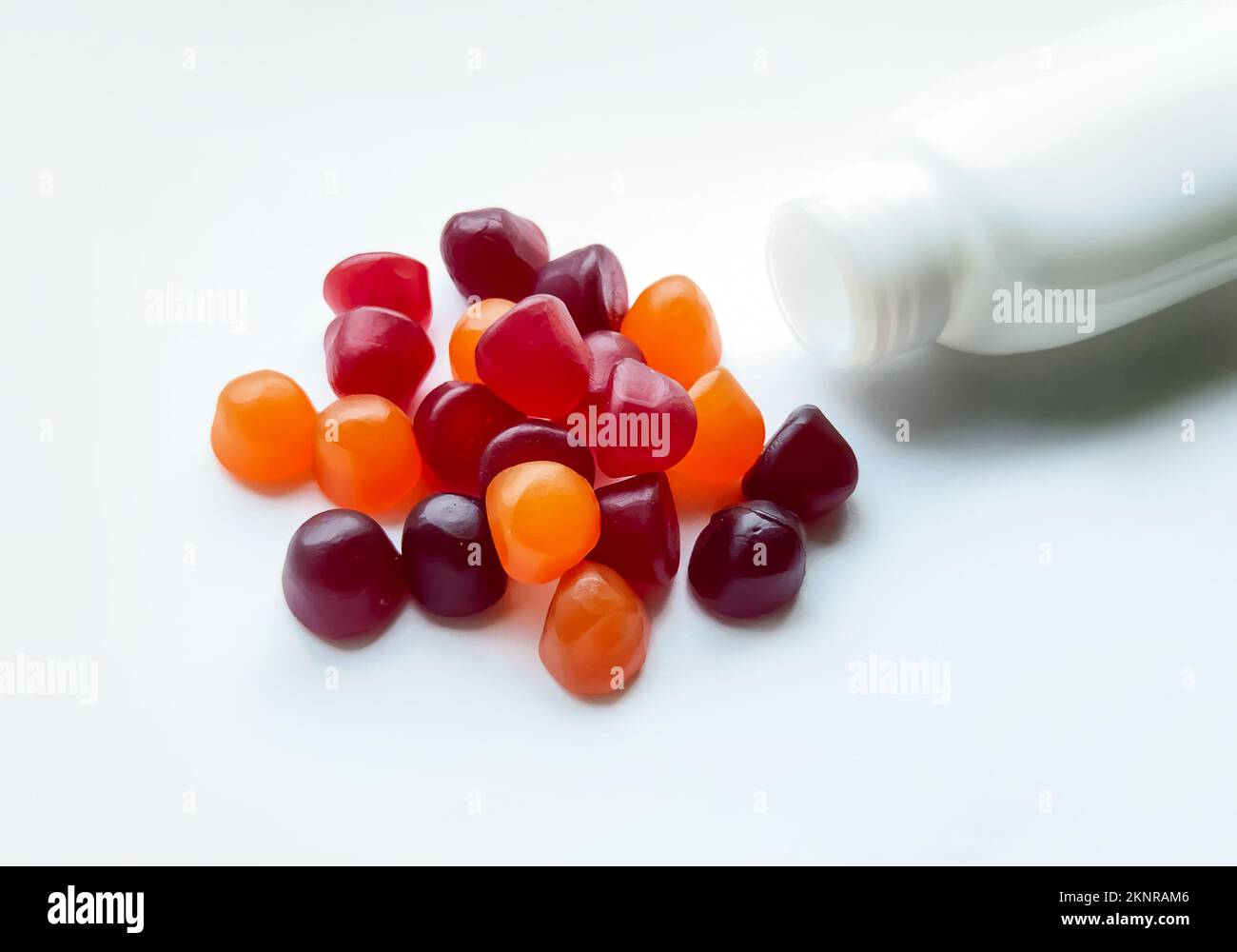 Gruppe roter, orangefarbener und violetter Multivitamingummi mit isolierter Flasche auf weißem Hintergrund Stockfoto