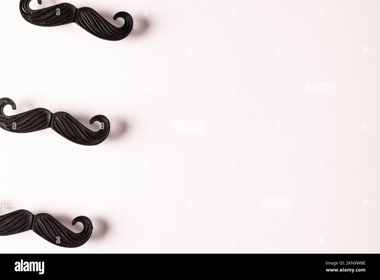 Komposition gefälschter Schnurrbärte auf weißem Hintergrund mit Kopierraum Stockfoto