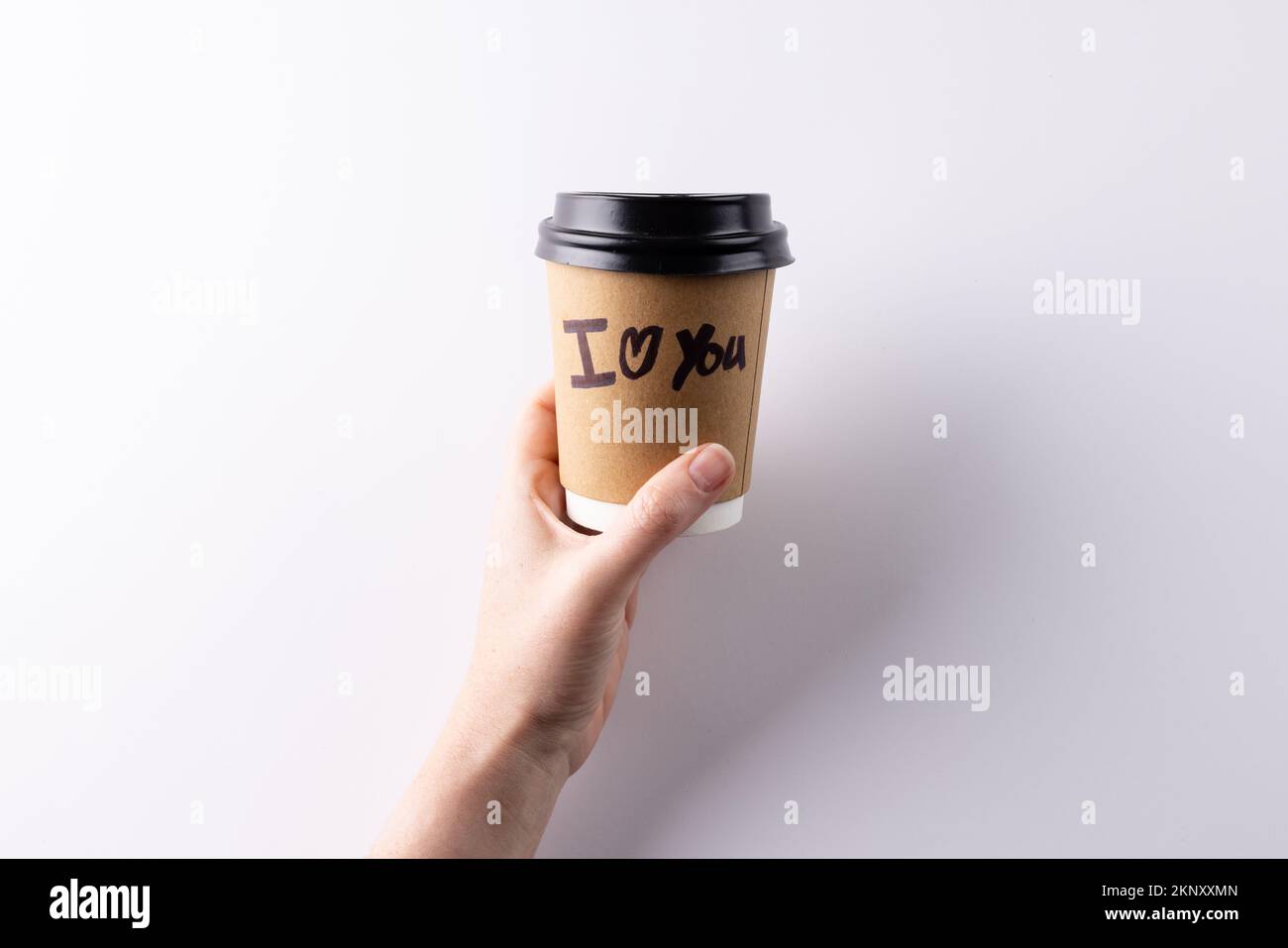 Hand halten Kaffeetasse zum Mitnehmen mit "ich liebe dich", du schreibst darauf, mit Kopierraum Stockfoto