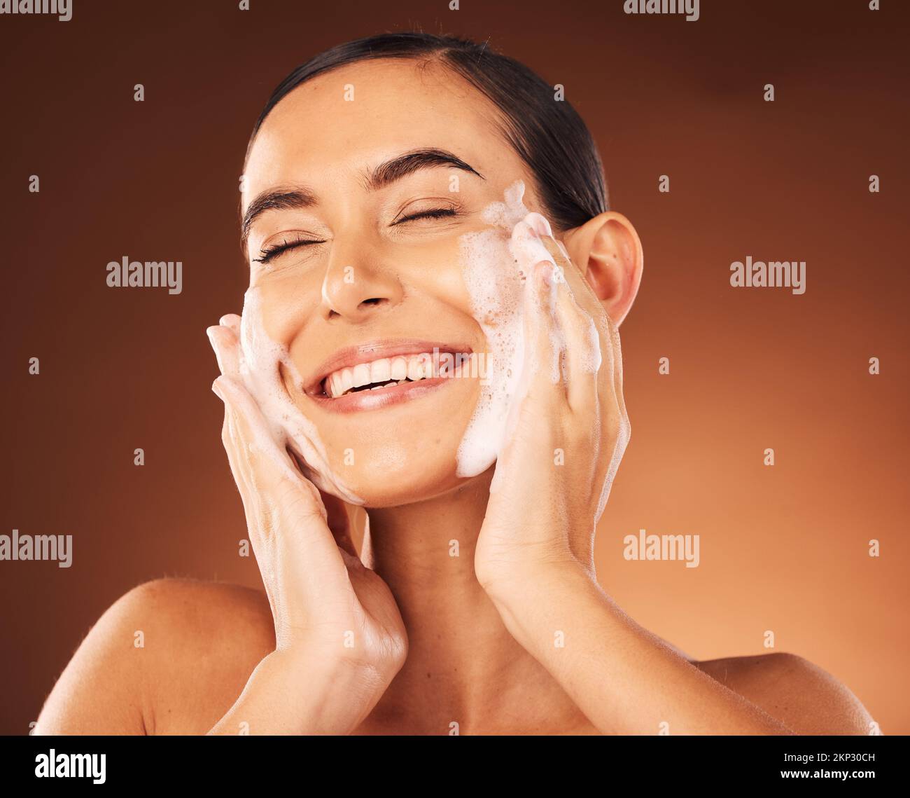 Hautpflege, Hände und Schaum im Gesicht für eine Reinigung mit Lächeln, Glück und Wellness im Spa. Gesichtswäsche, luxuriöse Kosmetiktherapie und Selbstpflege mit Seife Stockfoto