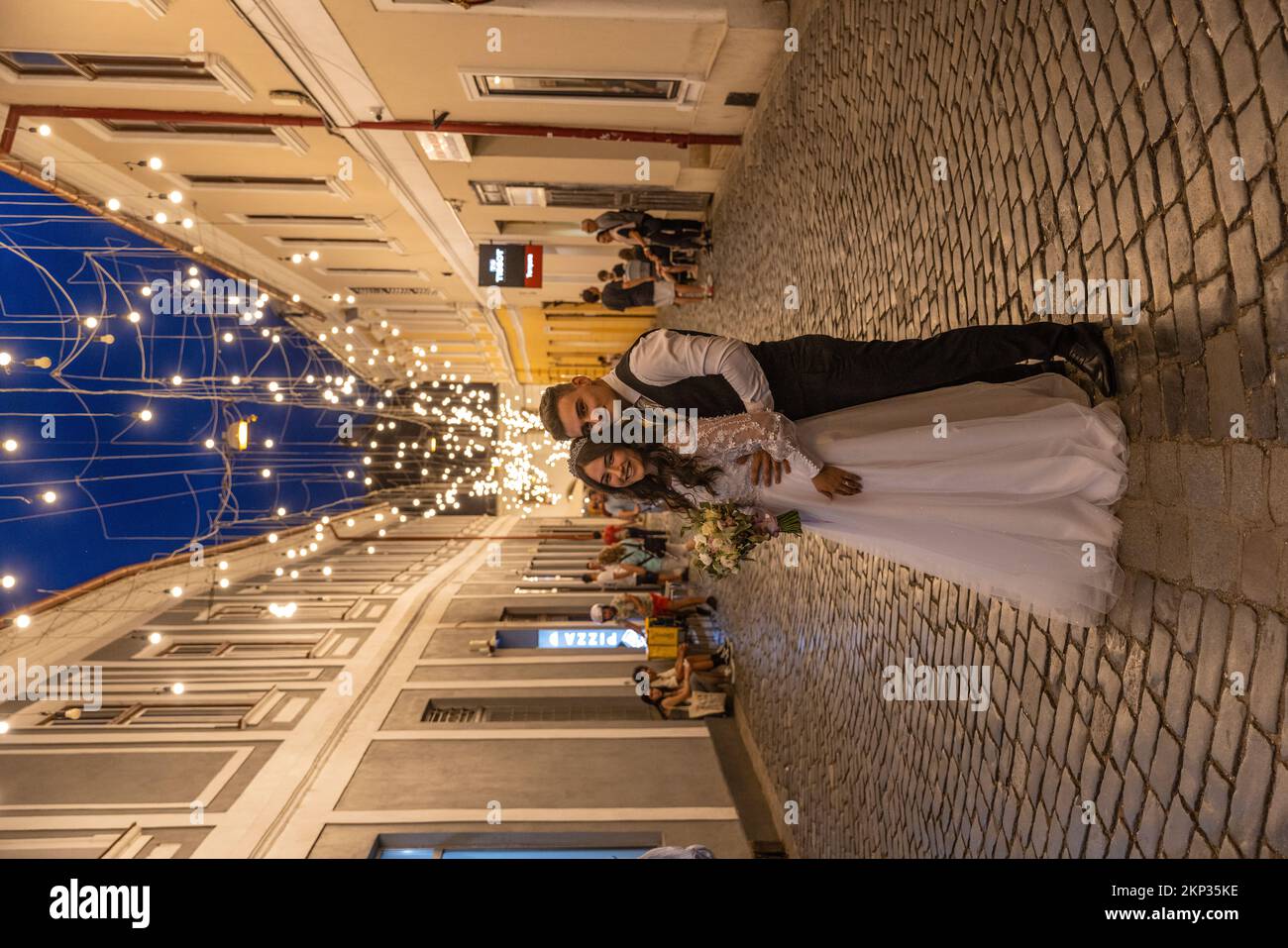 Hochzeitspaar entlang der beleuchteten Fußgängerzone in der Altstadt von Cluj-Napoca, Rumänien Stockfoto