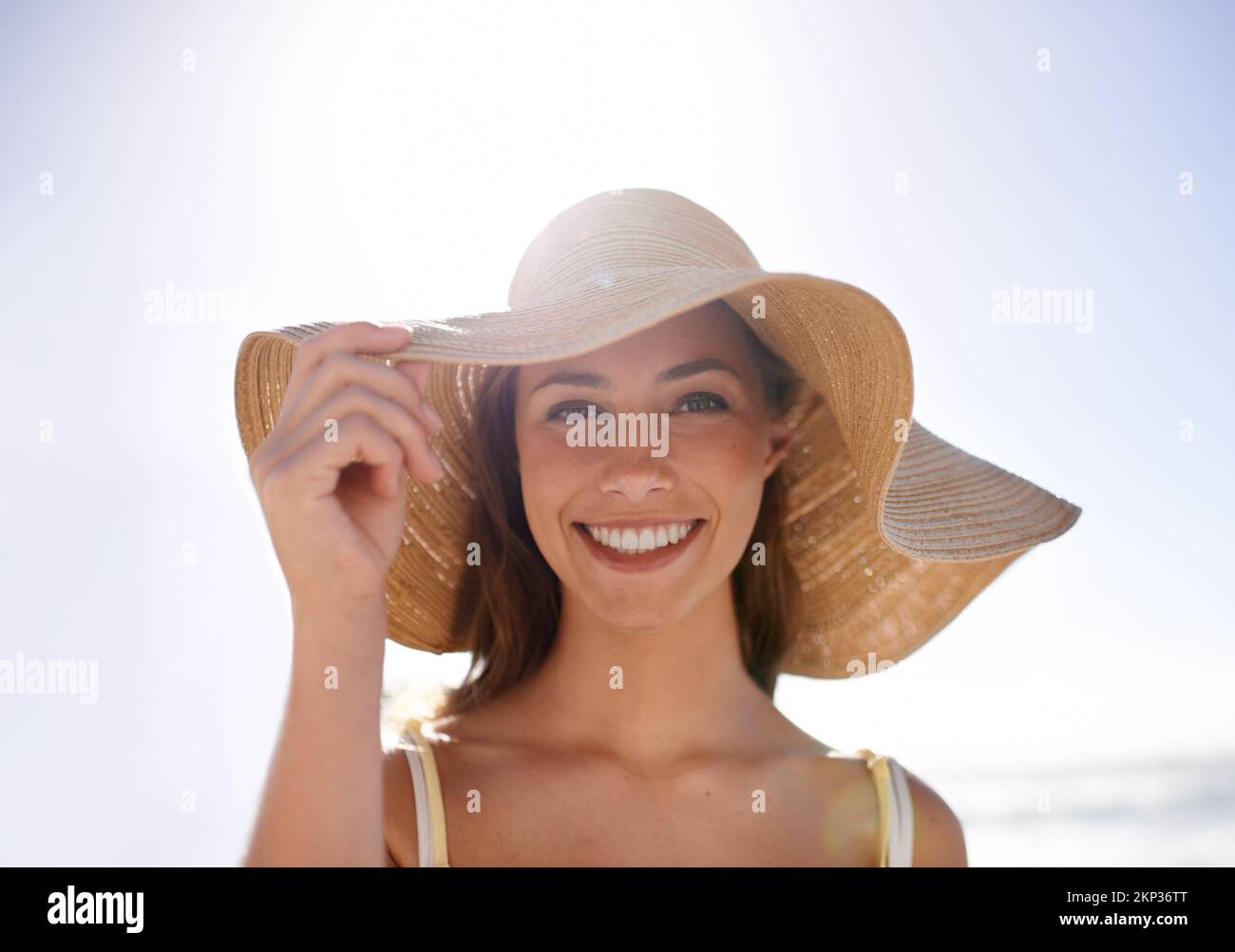 Sie fühlt sich sommerlich in ihrem Sonnenhut. Eine junge Frau mit Sonnenhut am Strand. Stockfoto