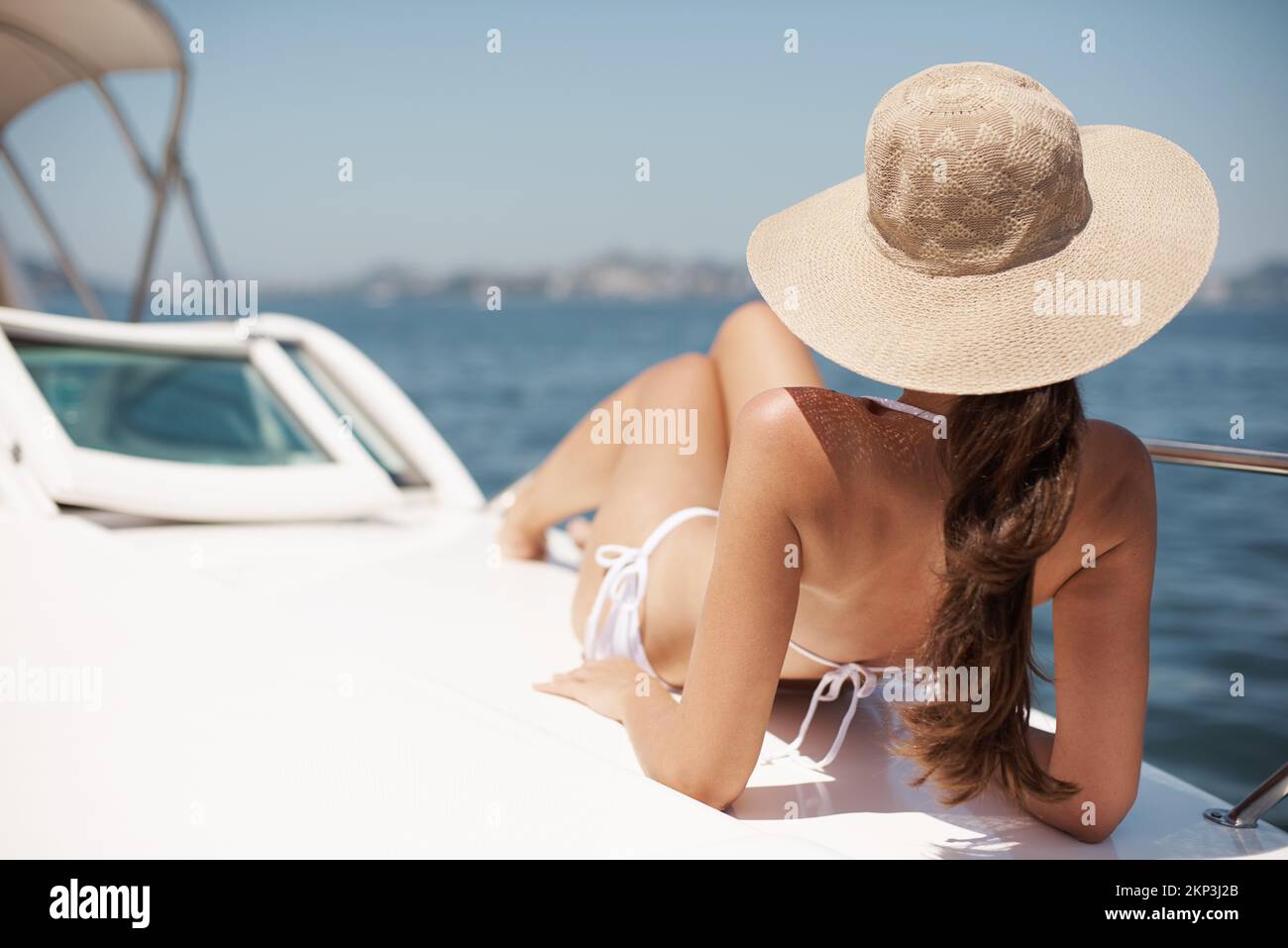 Lebensstil der Reichen und Berühmten. Eine attraktive junge Frau, die sich auf dem Deck einer Luxusyacht bräunt. Stockfoto