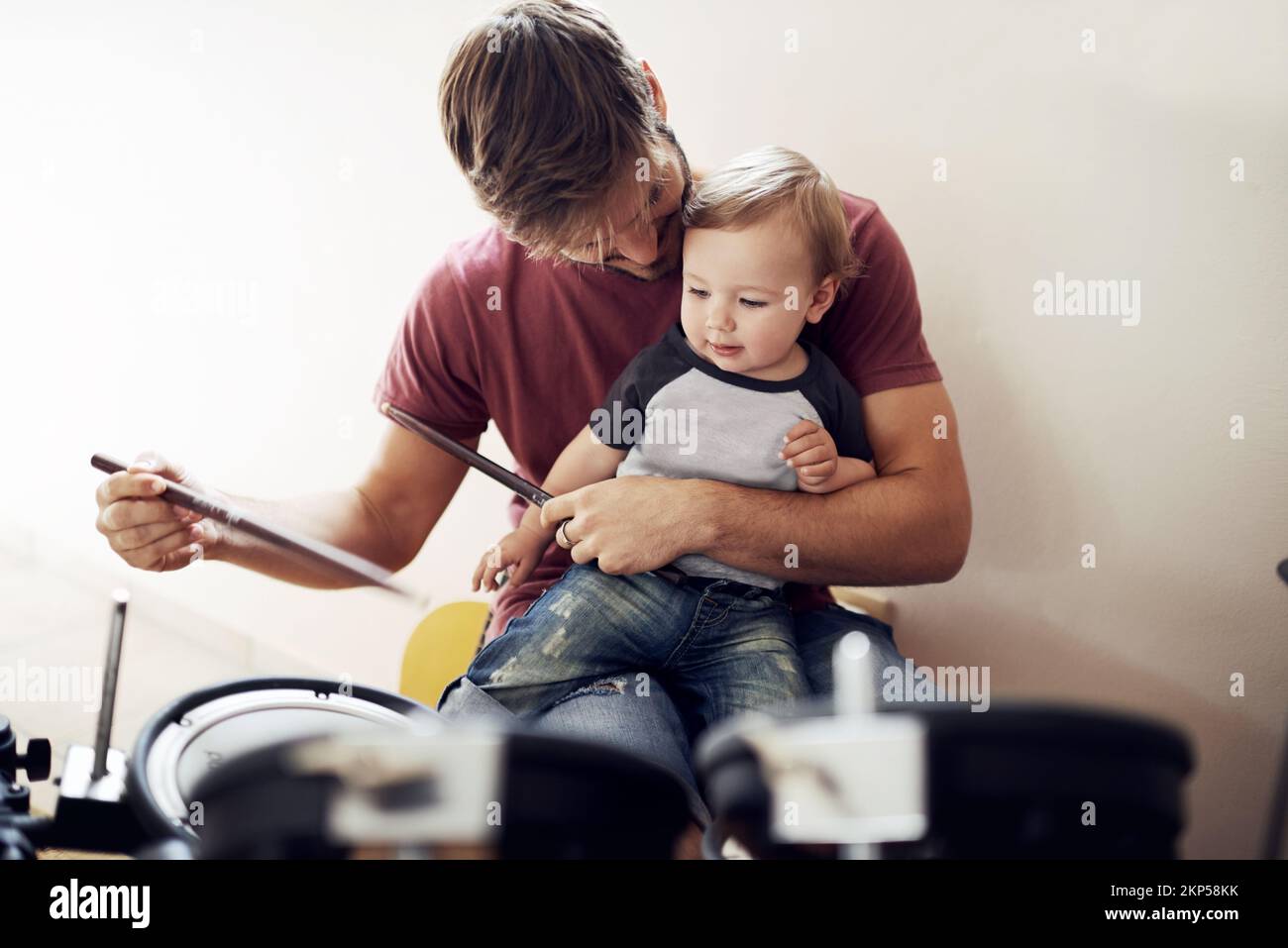 Listen....can Sie hören es. Ein hübscher junger Vater lehrte seinen jungen Sohn zu Trommeln. Stockfoto