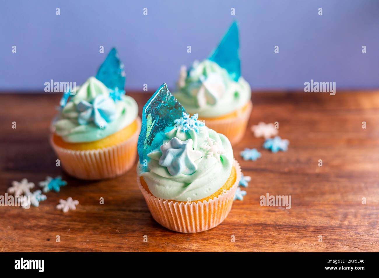 Hausgemachter blauer Cupcake auf einem Holzschreibtisch. Winter- und weihnachtsthema, Schneeflocken auf blauem Eis, frisch und selbstgebacken süß. Stockfoto