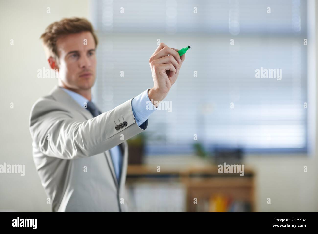 Zukunftsplanung. Ein seriöser junger Geschäftsmann, der auf Glas mit einem Marker schreibt. Stockfoto