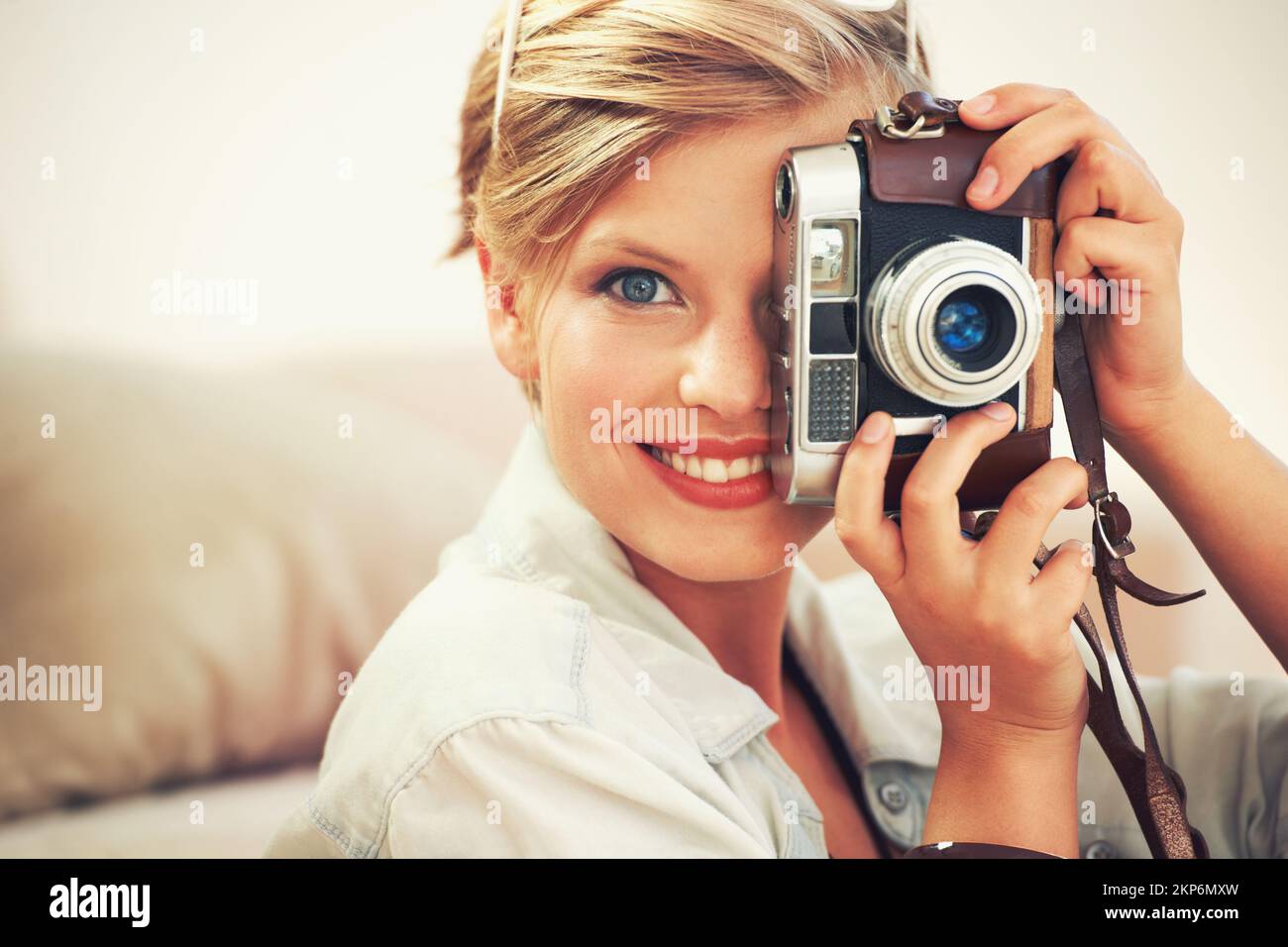 Ich übe für meinen nächsten Urlaub. Eine junge Frau, die zu Hause Fotos mit ihrer Kamera macht. Stockfoto Ich übe für meinen nächsten Urlaub. Eine junge Frau, die zu Hause Fotos mit ihrer Kamera macht. Stockfoto