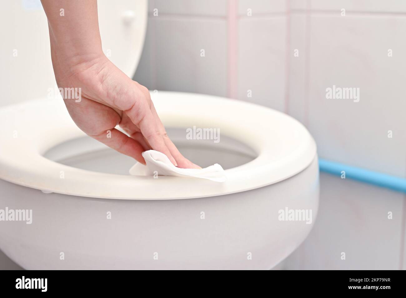 Eine Nahaufnahme der Hand einer Frau, die den Toilettensitz mit einem feuchten Tuch reinigt Stockfoto