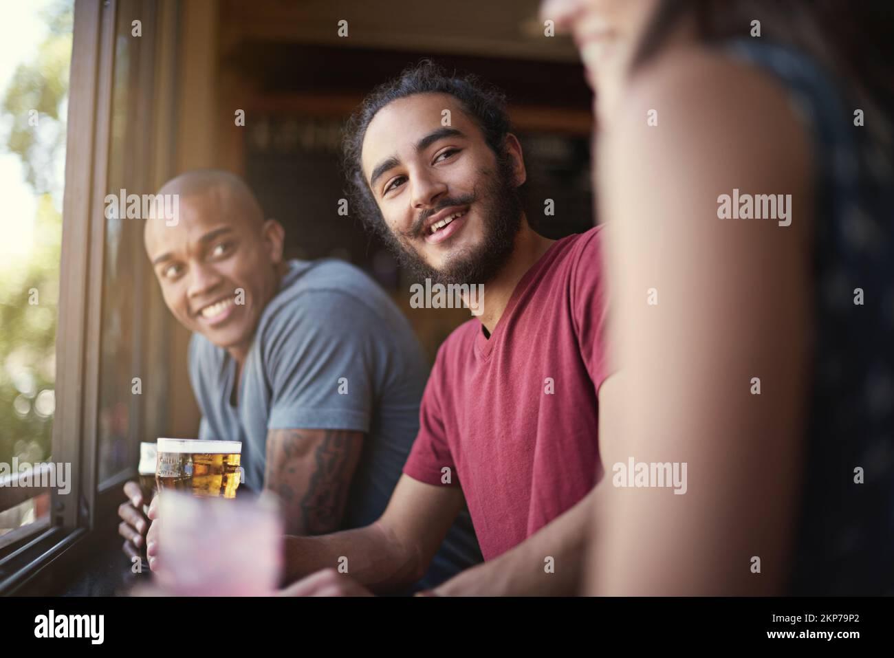 Drinks teilen und lachen. Eine Gruppe von Freunden, die sich im Pub amüsieren. Stockfoto