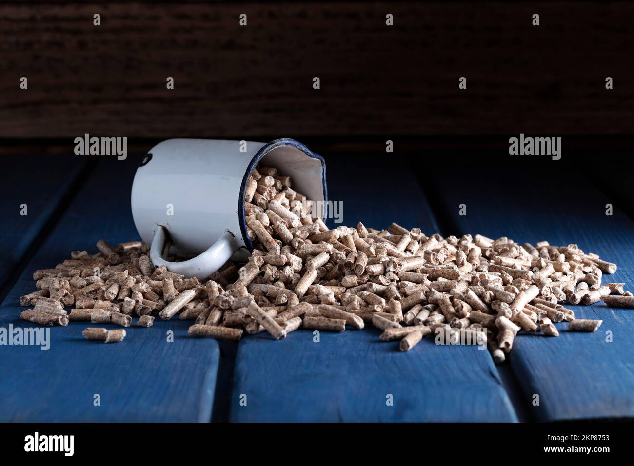 Holzpellets mit emaillierter Tasse auf blauem Holzhintergrund, Studioaufnahme, Deutschland, Europa Stockfoto
