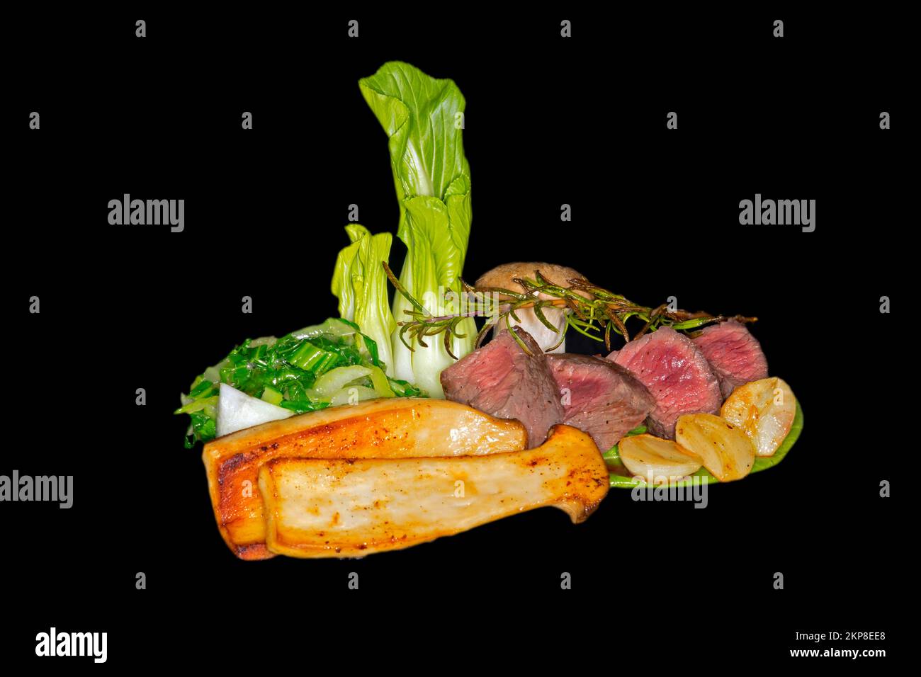 Mittelgeröstetes Wildfilet mit pak Choi, Kräuterpilzen, Rosmarin-Zweig und Knoblauch, Lebensmittelfotografie mit schwarzem Hintergrund Stockfoto