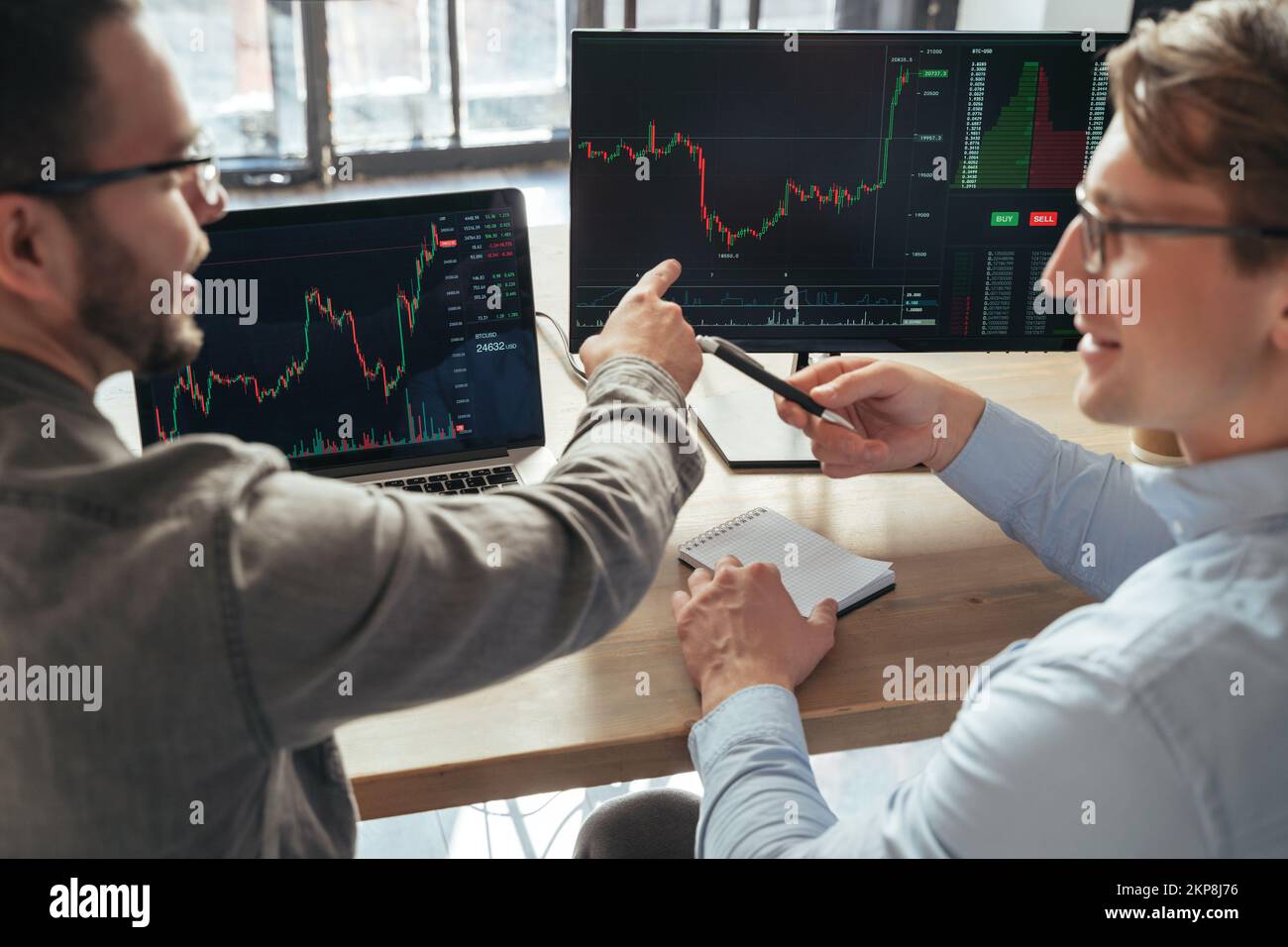 Zwei Männer, die Anleger an einem Tisch vor dem pc verkaufen, analysieren den Preisfluss, diskutieren Rate, Aktionen, überwachen Datendiagramme für Aktien. Selektiver Fokus auf den Computerbildschirm Stockfoto