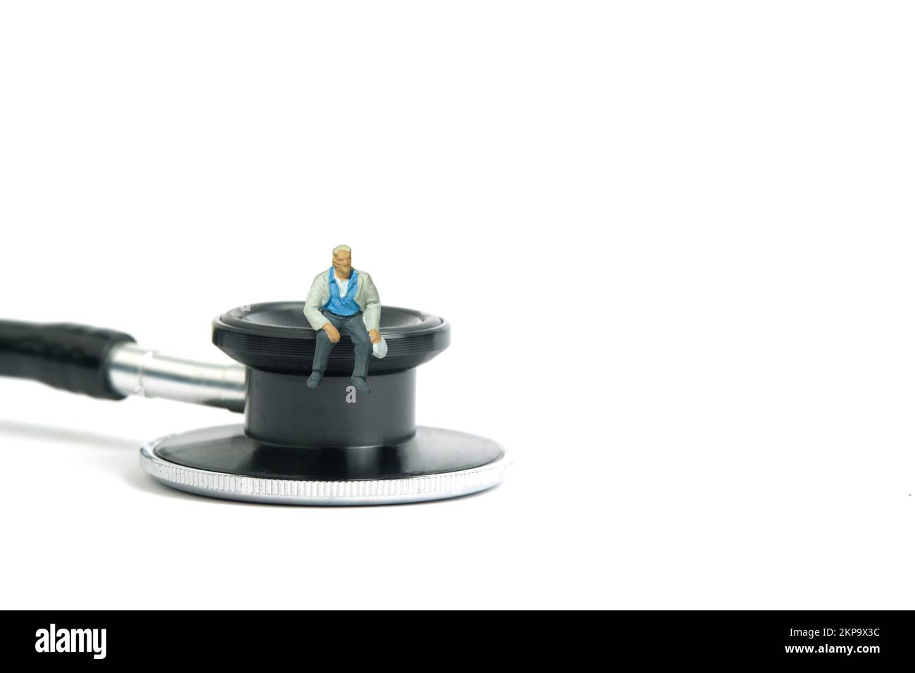 Miniatur-Menschen-Spielzeug-Figuren-Fotografie. Arbeiterkrankenversicherungskonzept. Männer, die über dem Stethoskop sitzen. Isoliert auf weißem Hintergrund. Bild-ph Stockfoto
